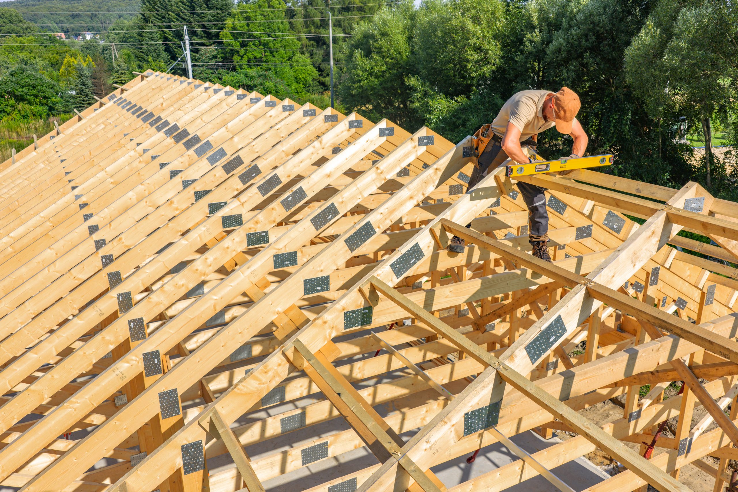 Construction Worker Carpenter Measuring Roof Trusses on a Sunny Day Outdoors